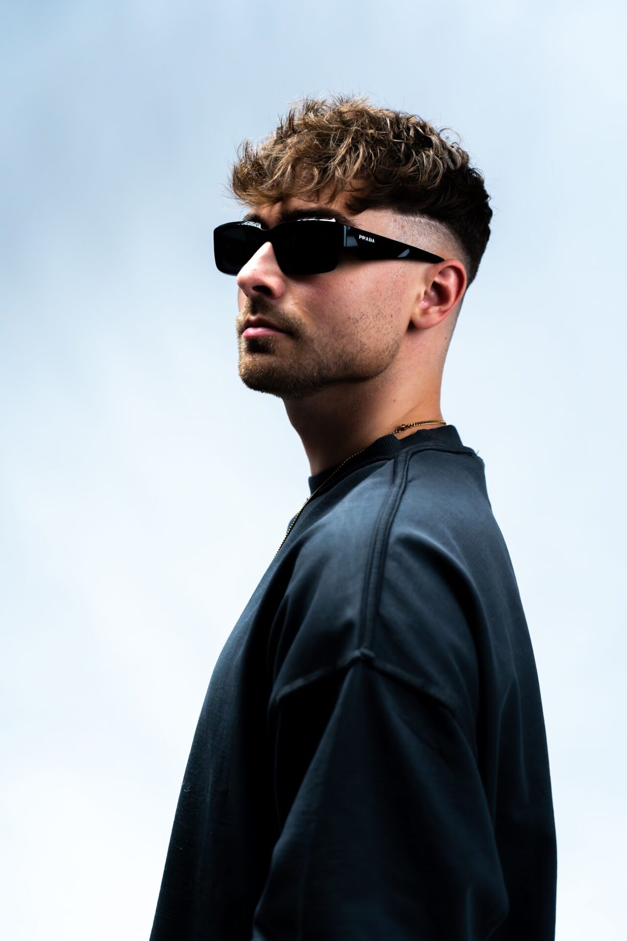 Hawkeys in profile with sunglasses against a pale blue backdrop